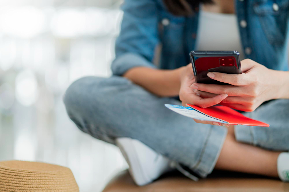 close-up-female-traveller-hand-hold-passport-using-smartphone-checking-online-boarding-departure-airport-terminalasian-female-sit-relax-wating-area-wwating-boarding-travel-concept